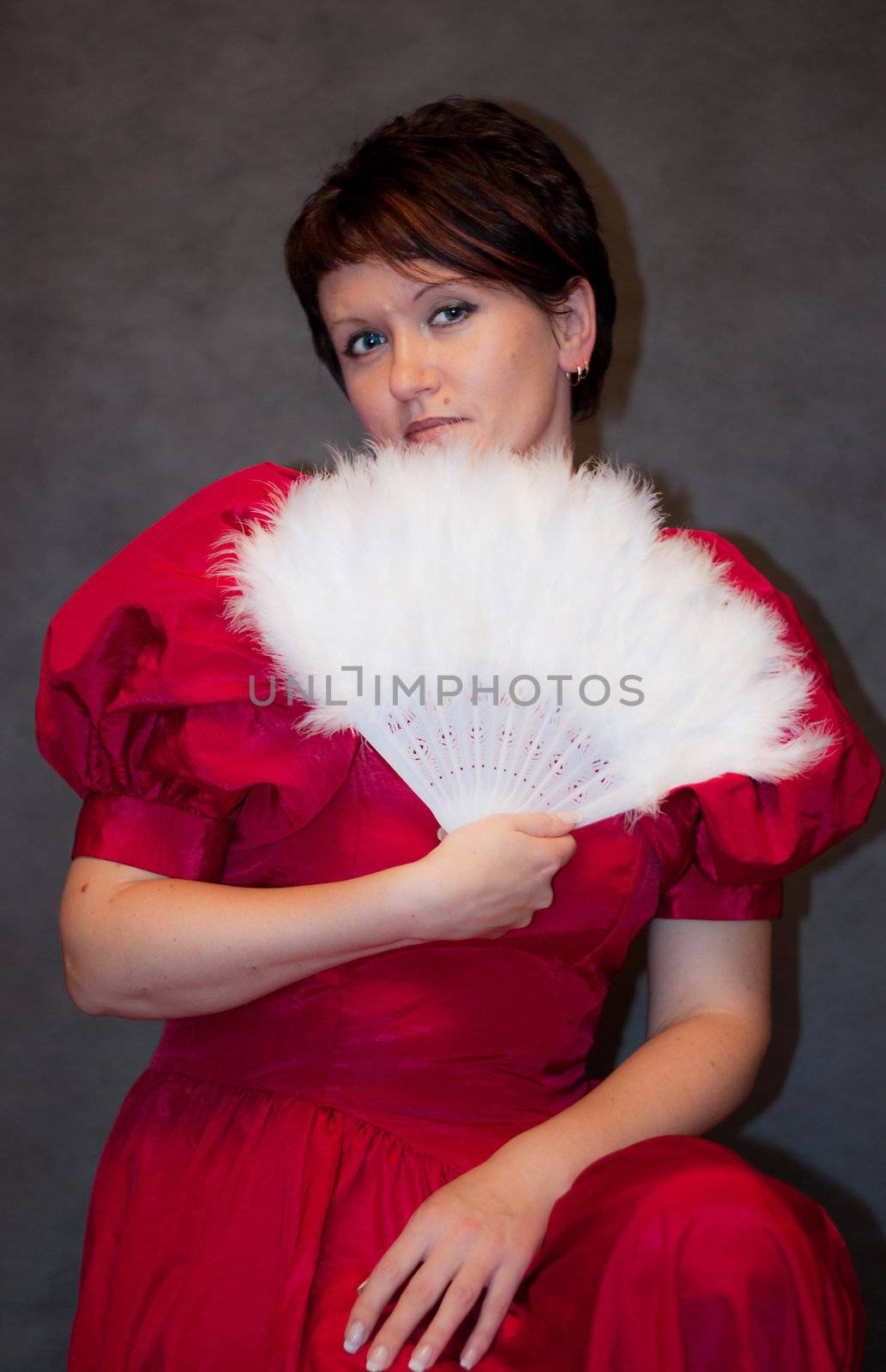 We see pretty Woman in red dress with white fan