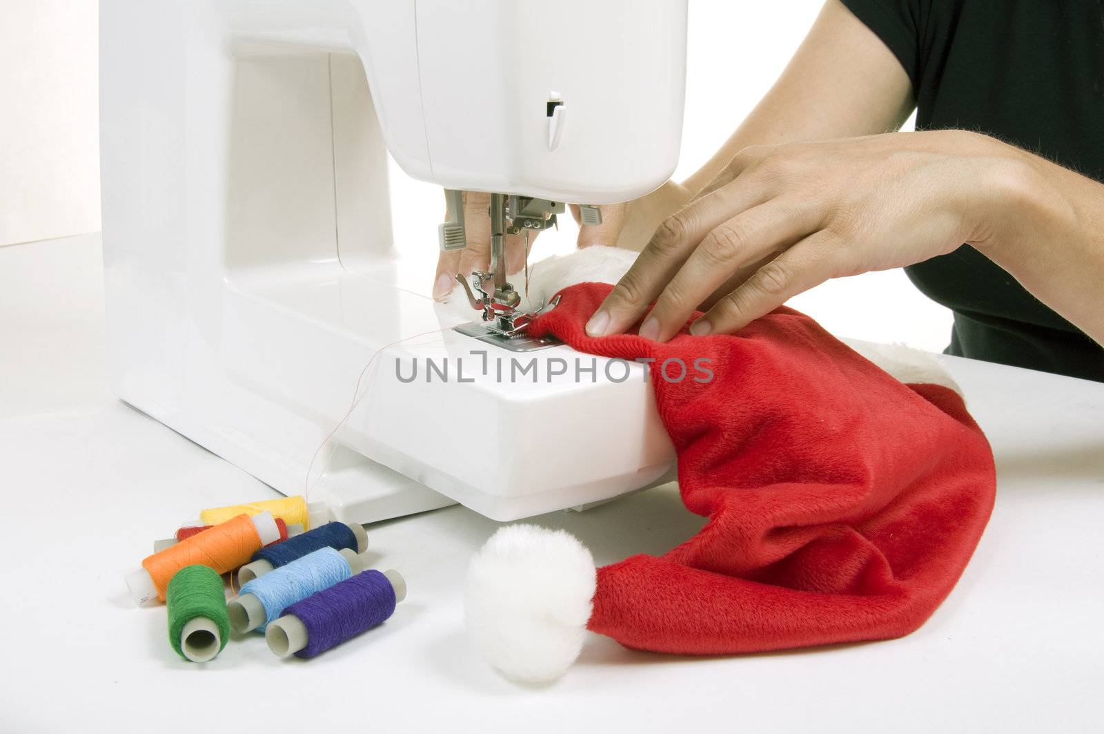 woman sewing a hat for Santa Claus on the sewing machine