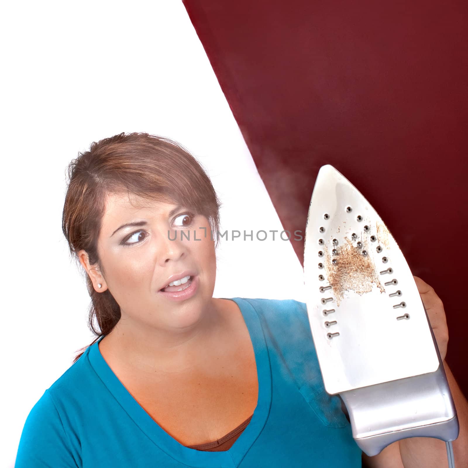 A young woman at home looking at her steaming household iron in disgust.