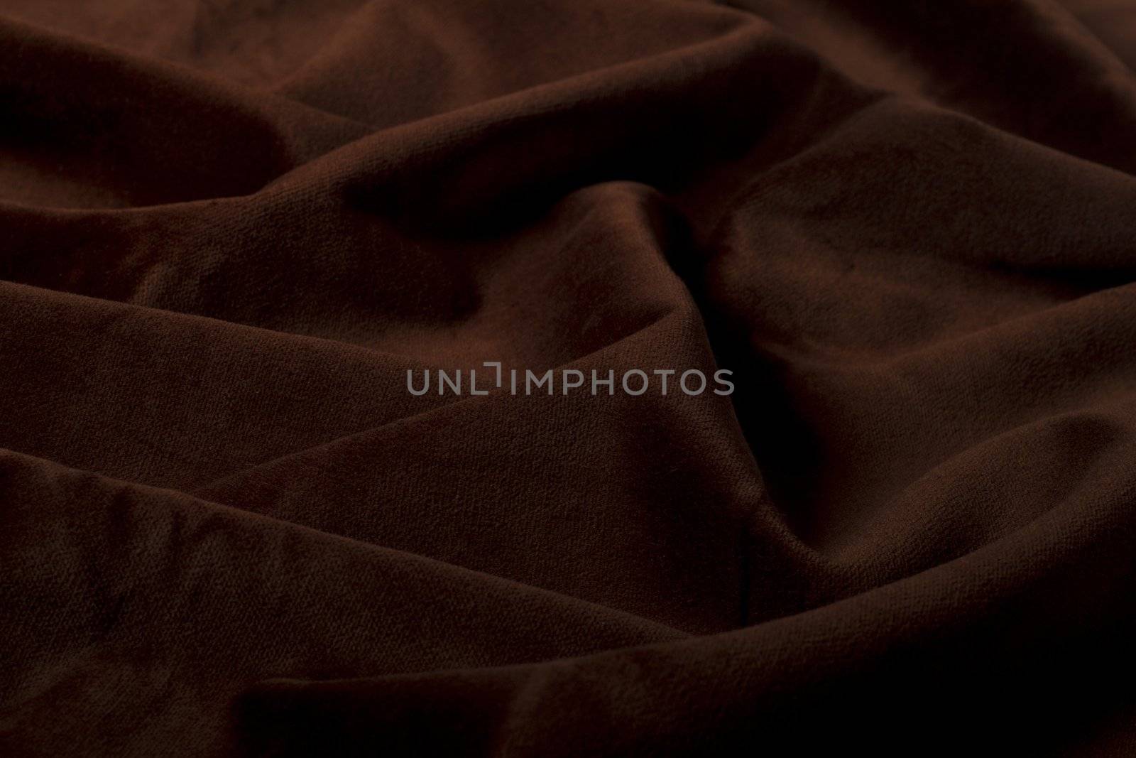 Close up view of a wrinkled dark brown silk fabric background.
