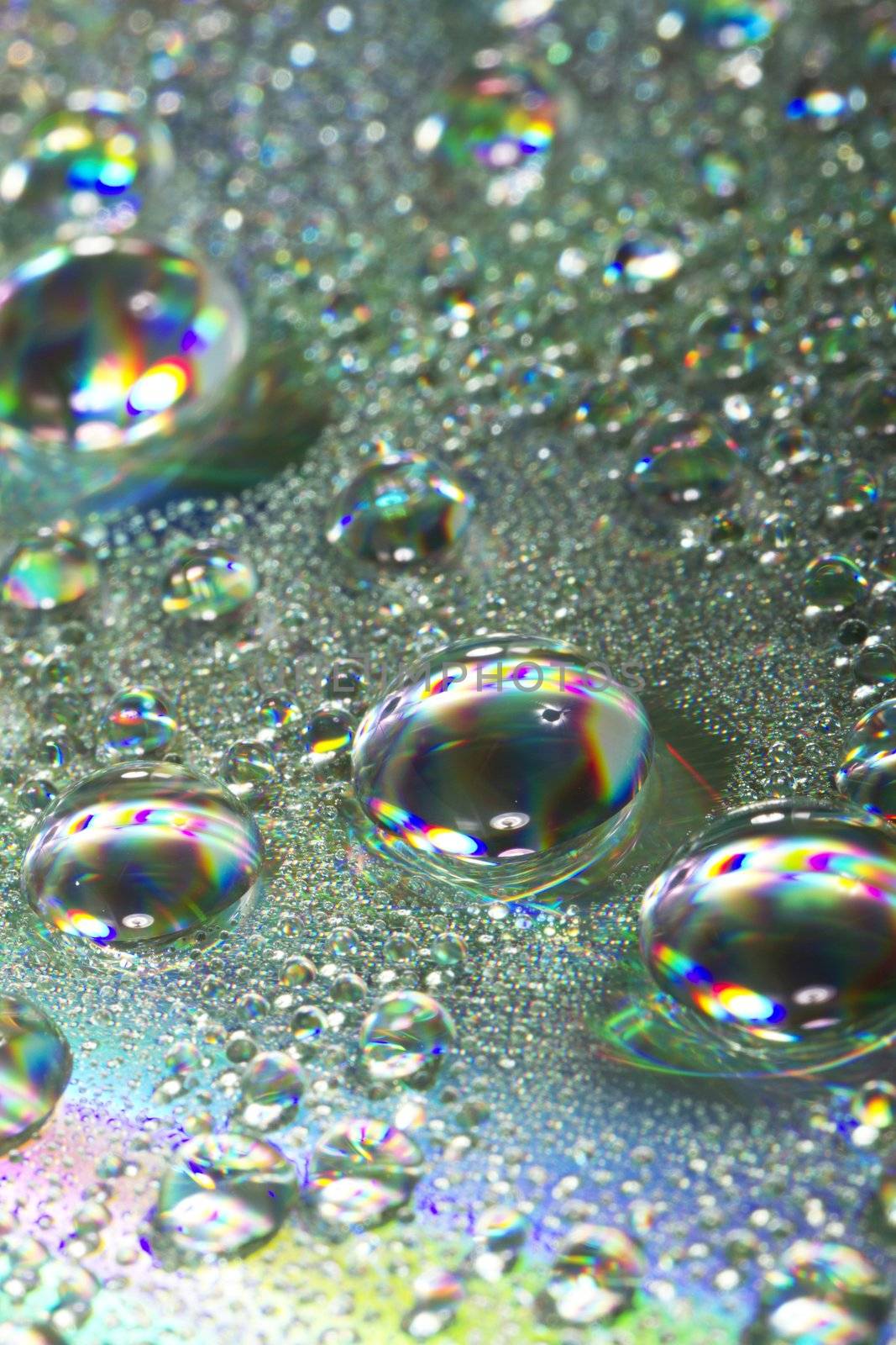 Close up view of many colorful and bright drops of water on a shiny surface.