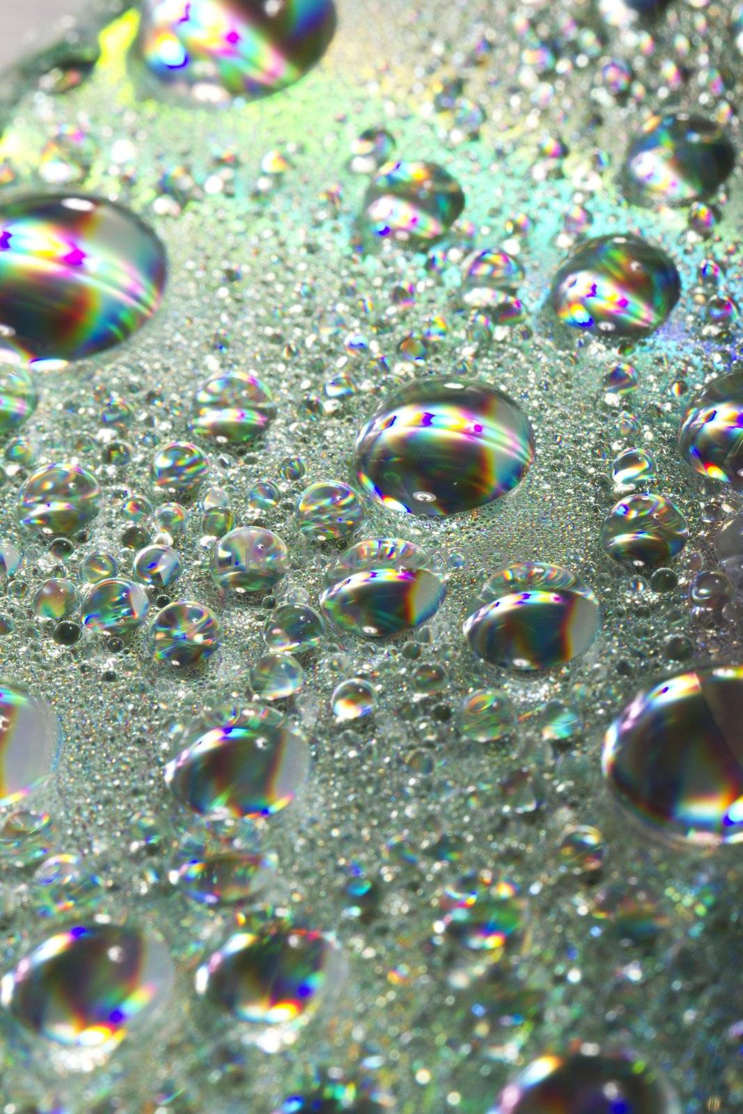 Close up view of many colorful and bright drops of water on a shiny surface.