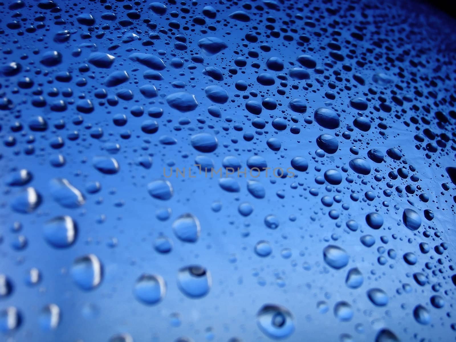 several water drops on a plastic surface with blue tones.