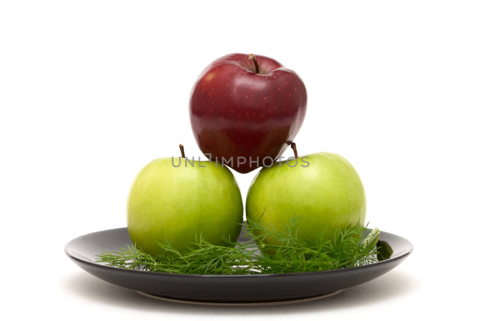 Three colored apples on a black plate on white background