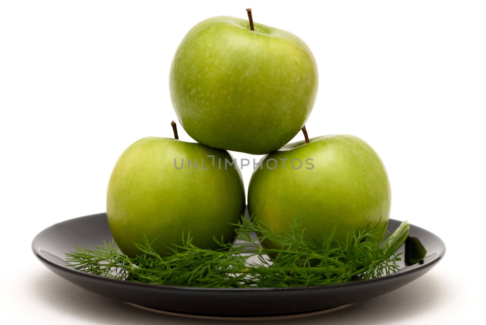 Three apples with dill on a black plate