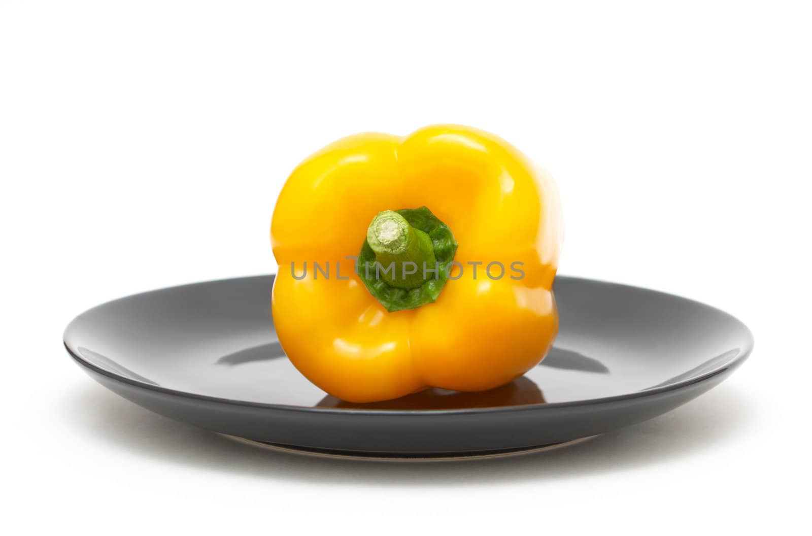Yellow pepper on black plate on a white background