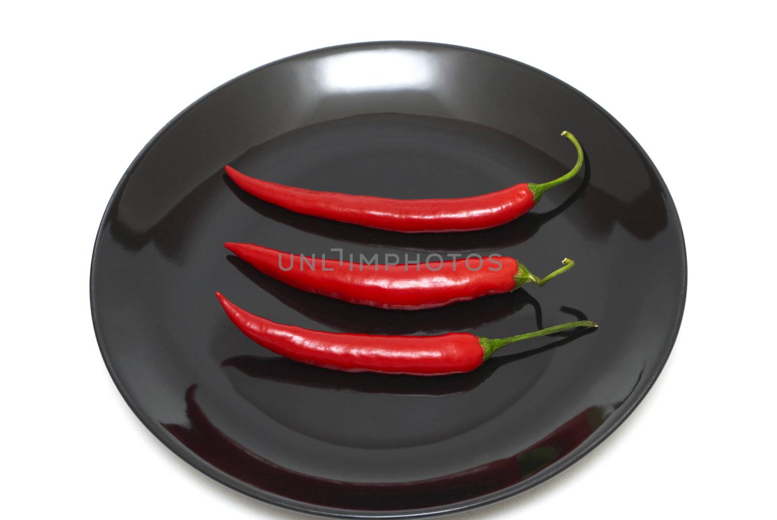 Tree red chili peppers on a plate by Olinkau