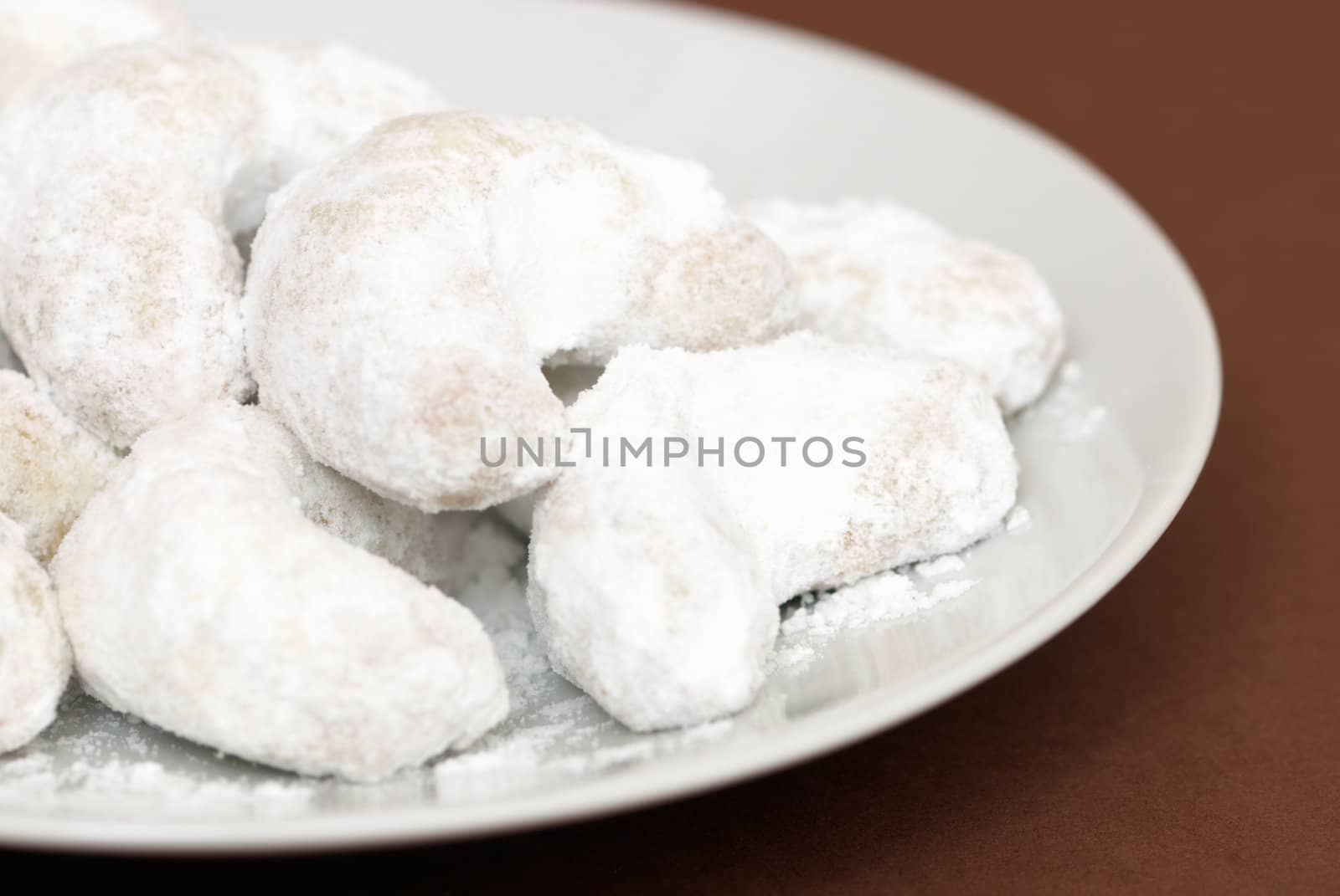 Little white cakes on a white plate on a brown background