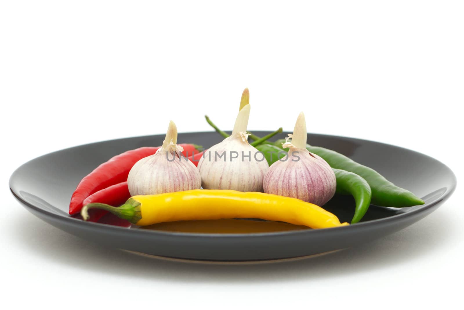 Three garlics with colored chili peppers on a plate