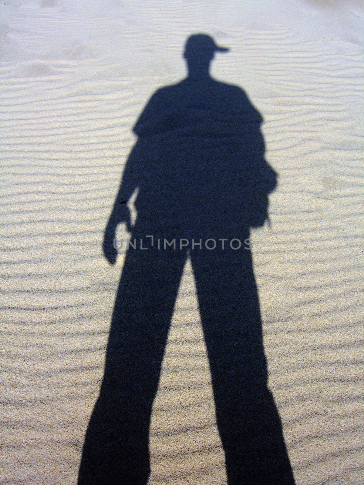 Shadow of a man reflected on the sand.