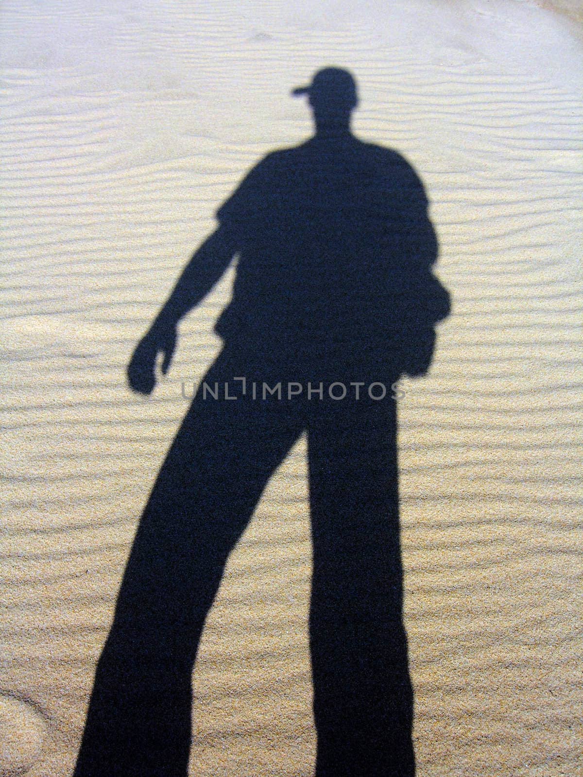 Shadow of a man reflected on the sand.