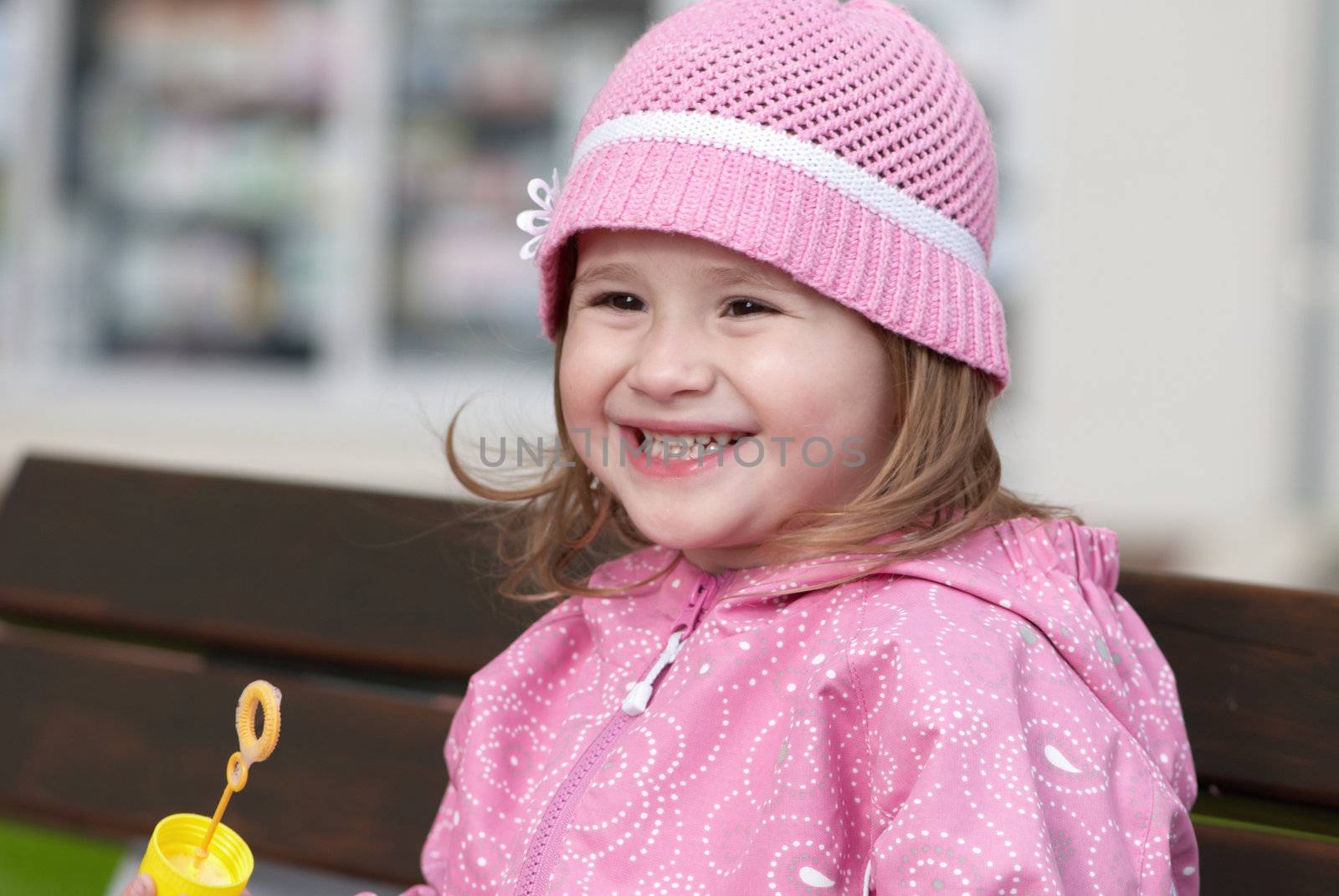 Smiling girl with a bubble wand on a branch
