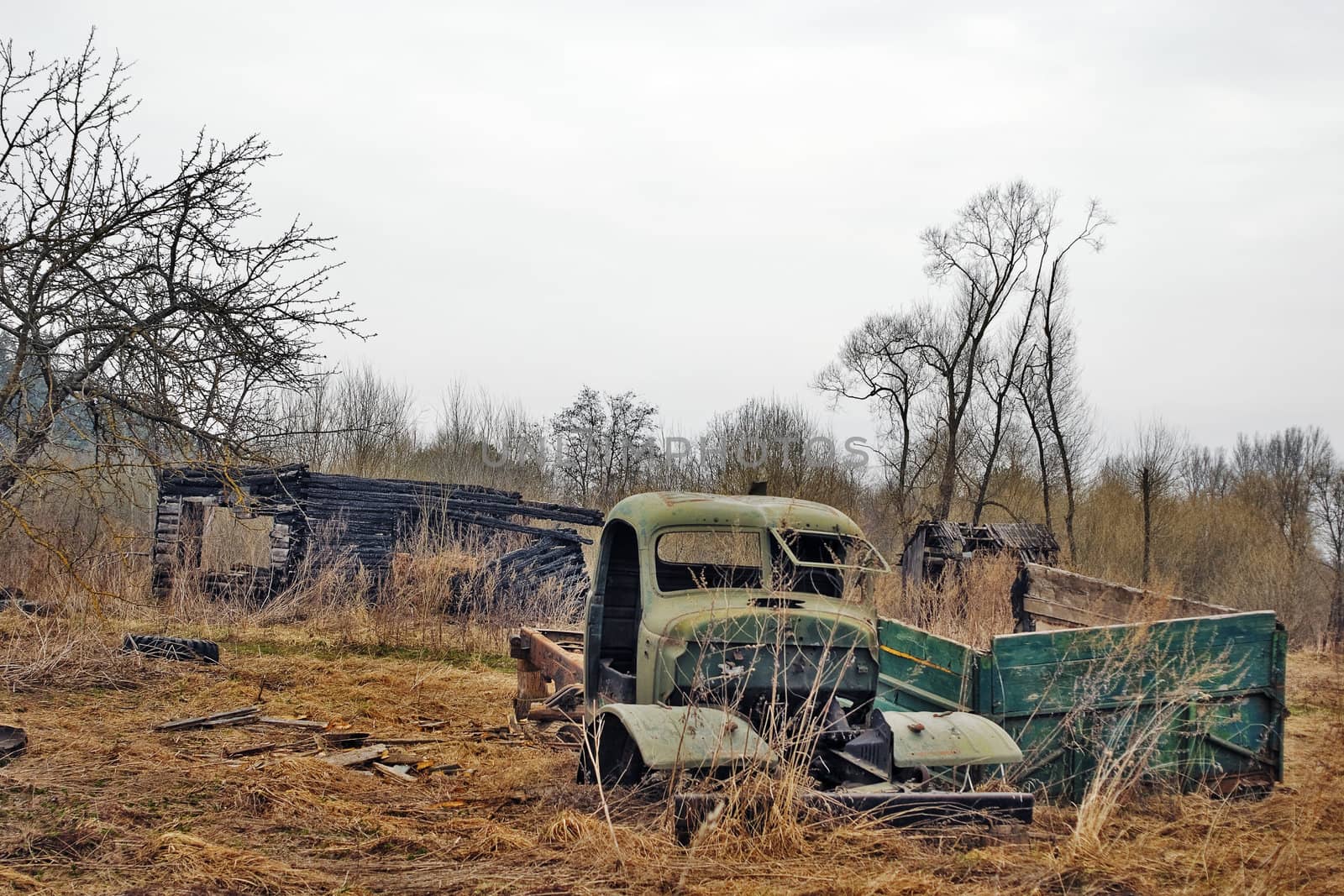 Rural landscape with the burnt down house and the lost broken car