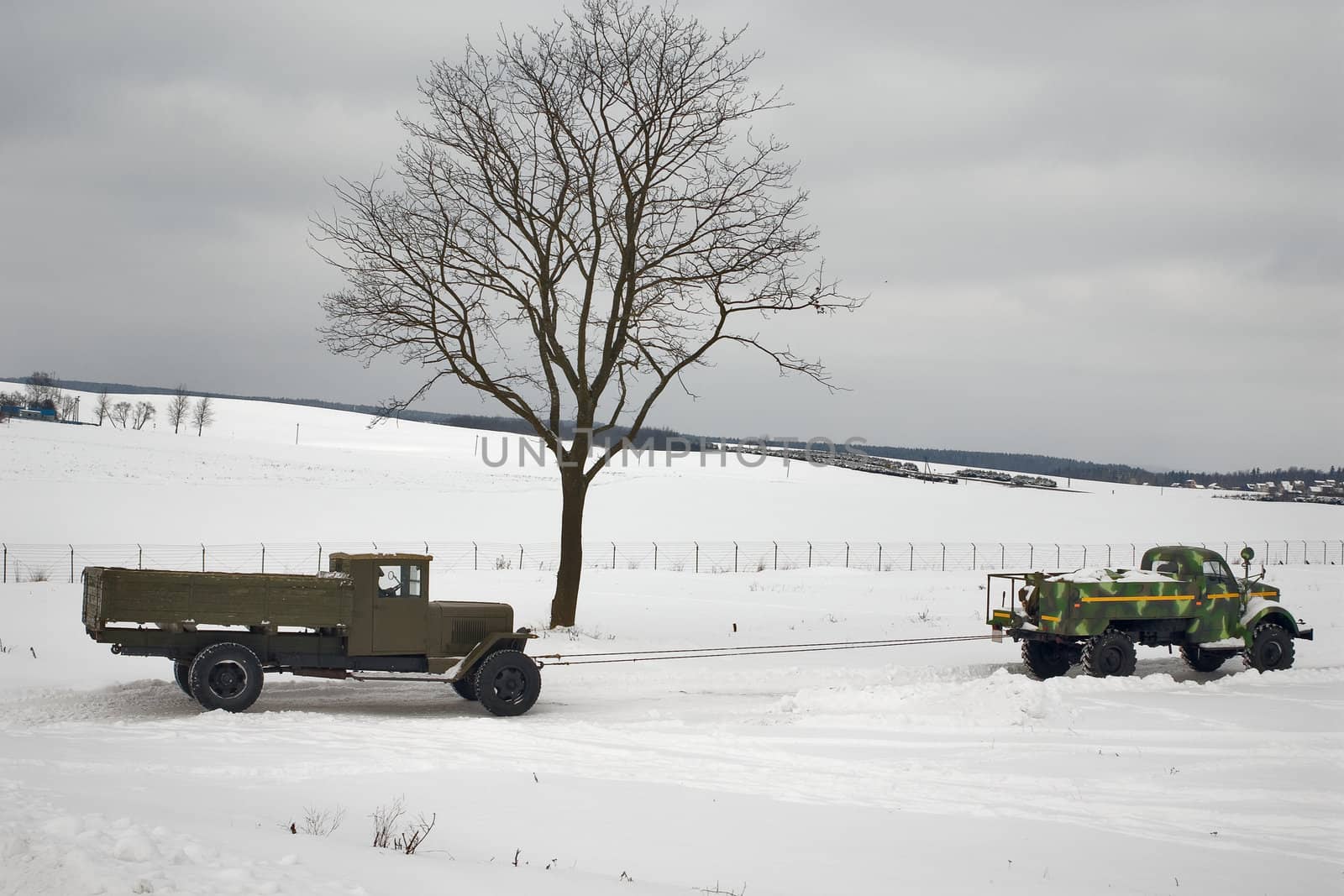 two old trucks in winter road. Car on a tow