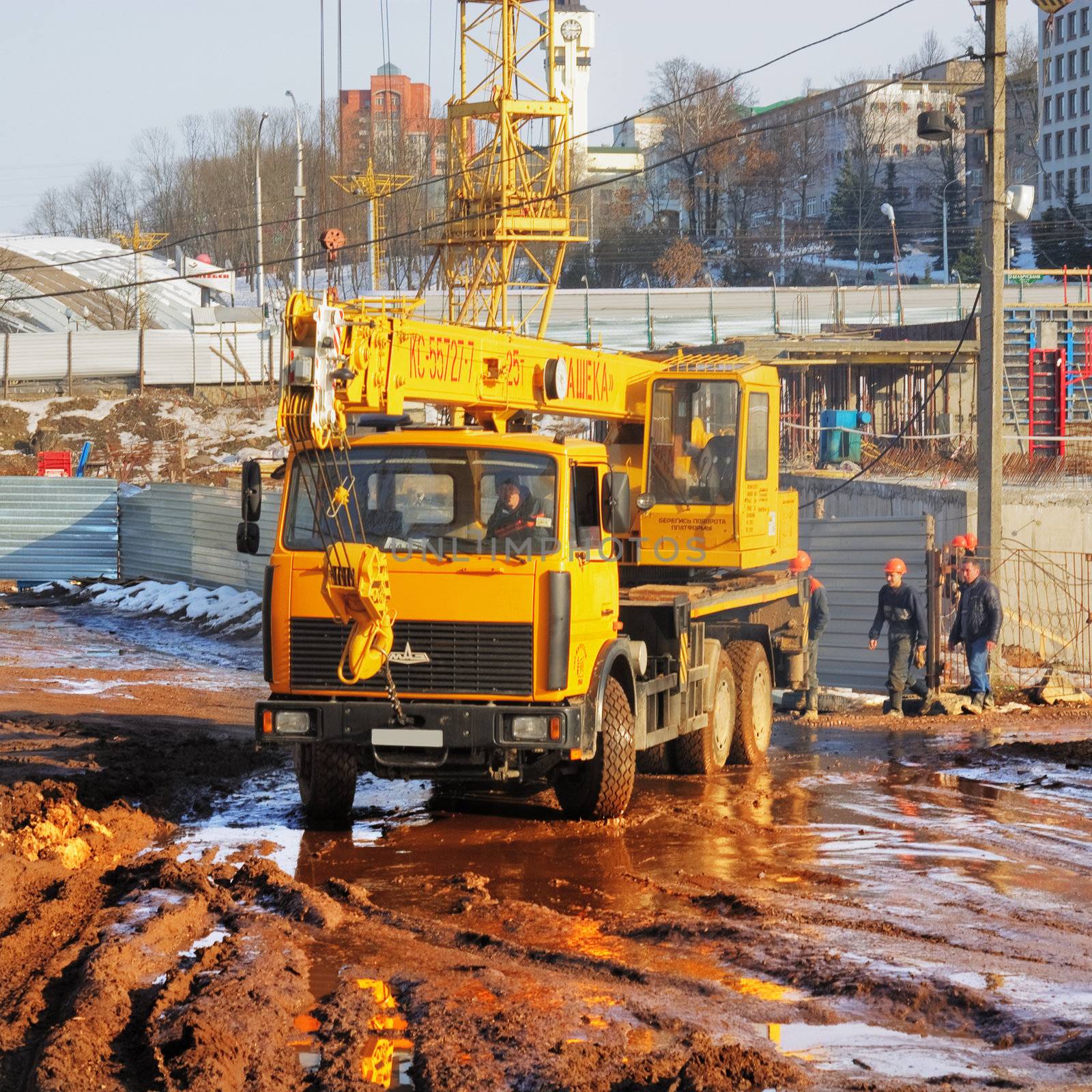 The yellow automobile crane goes on dirty road on building
