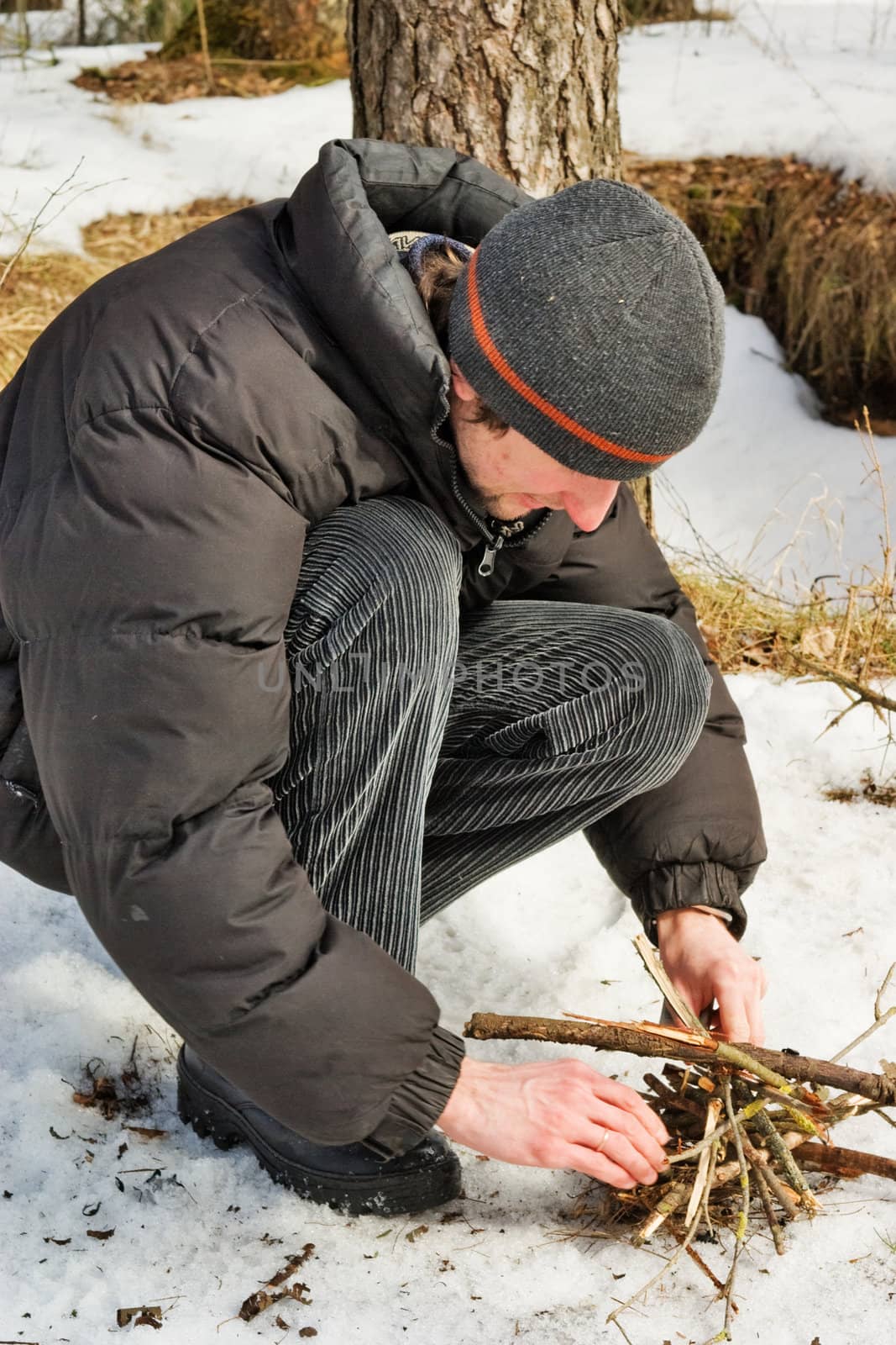 The young man kindles a firewood in winter wood