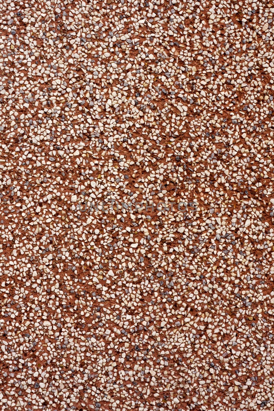 Close up view of a textured red wall with tiny stones.