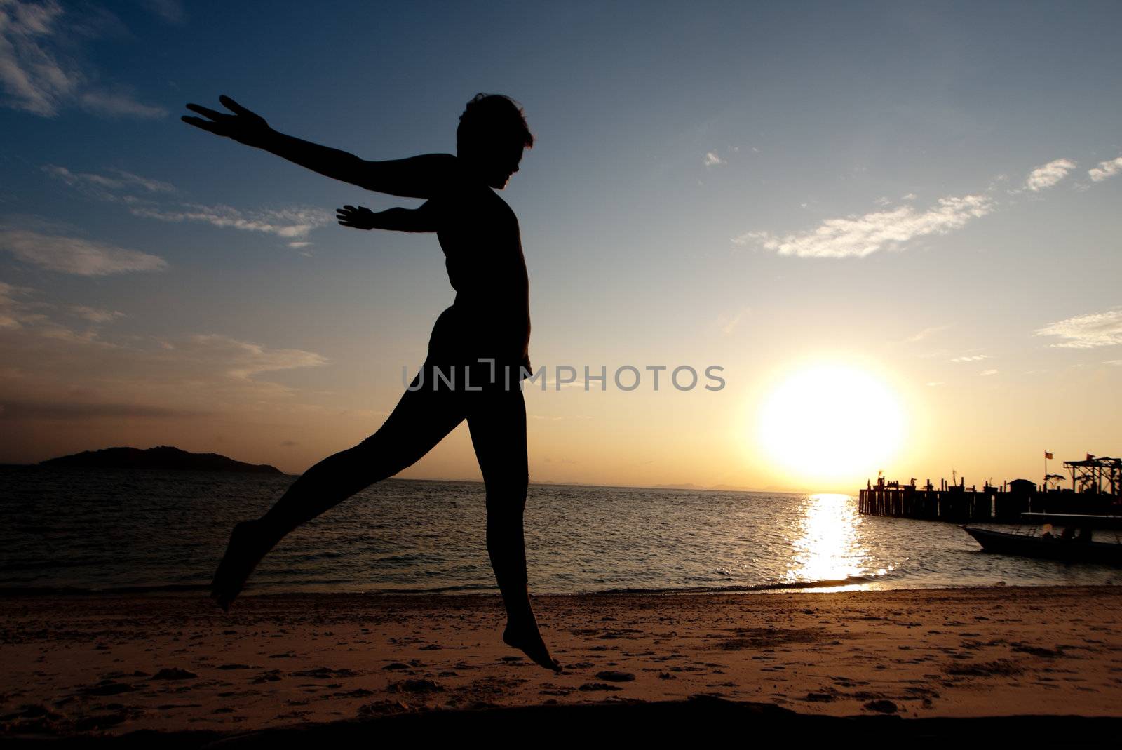 Silhouette of a young Asian woman jumping on the beach in Malaysia  at sunset