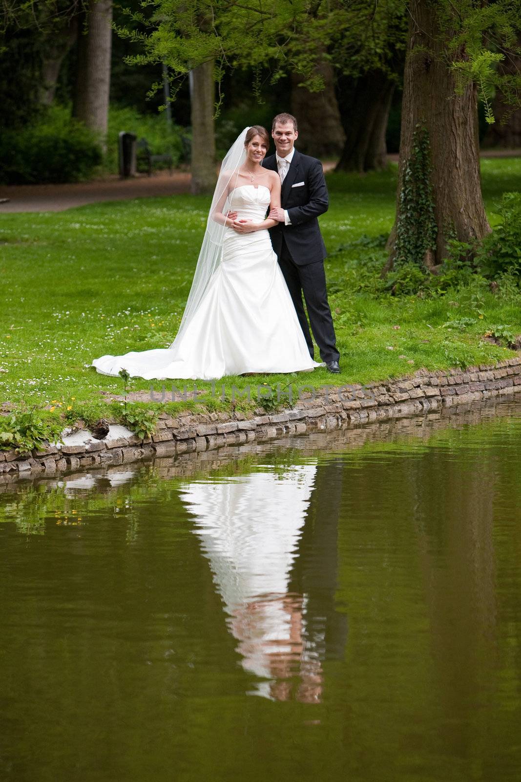 Bride and groom in the park near a pond reflecting
