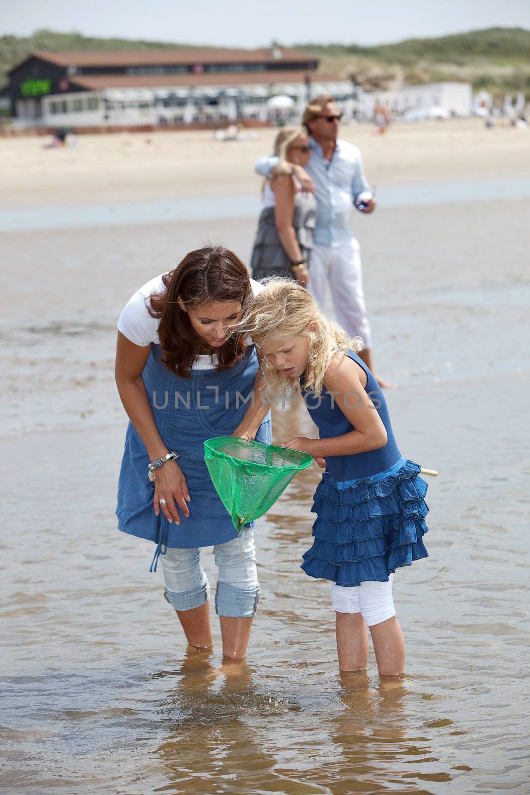 Mother and daughter on the beach with a little shrimpnet