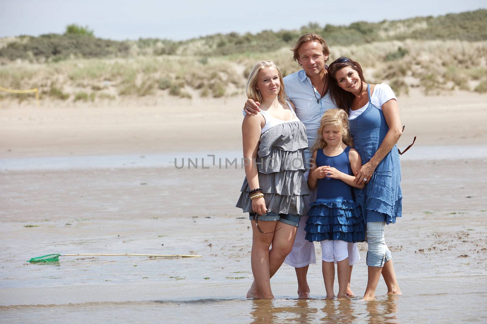 Beautiful young family standing on the edge of the water