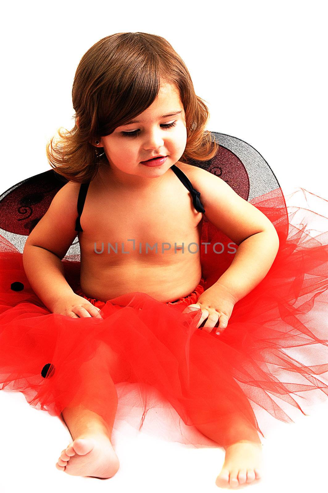 little girl playing and smiling in studio wearing red angle wings
