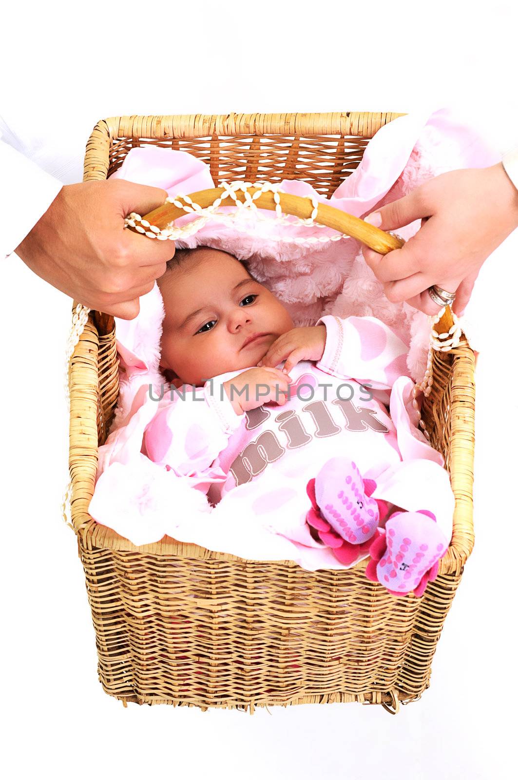 baby girl laying in a brown basket, white beads and big pink flower been held by parents
