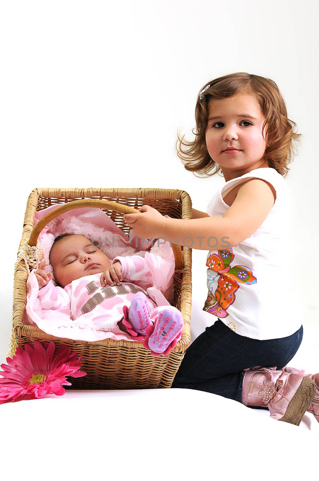 two sisters playing and smiling with baby in a basket with pink flower