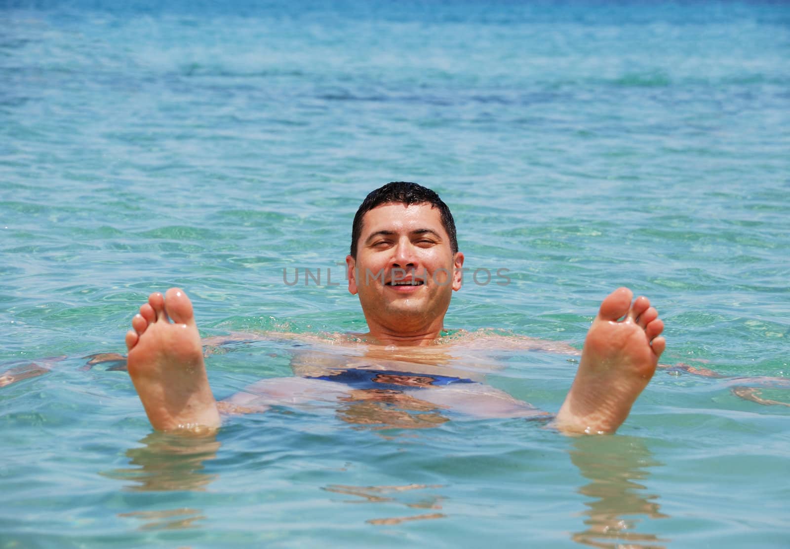 Young man floating in sea and smiling.