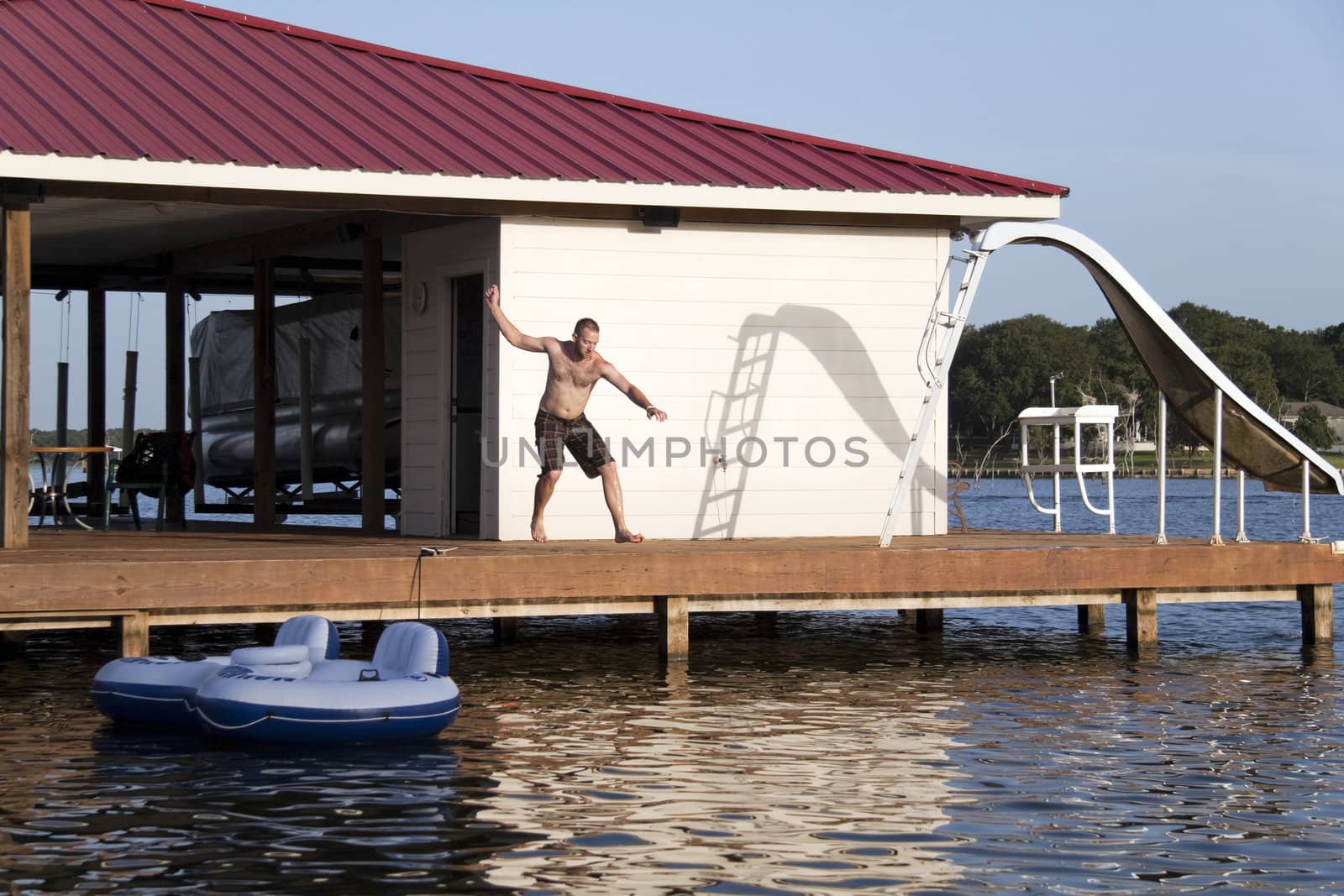 A man is doing a back flip off the end of a dock into the water