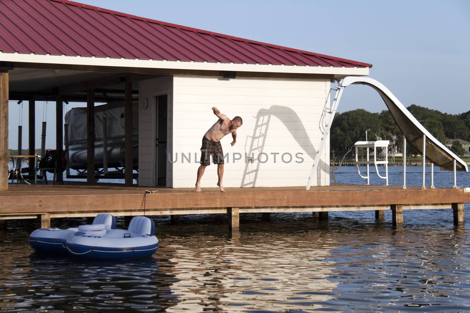 A man is doing a back flip off the end of a dock into the water
