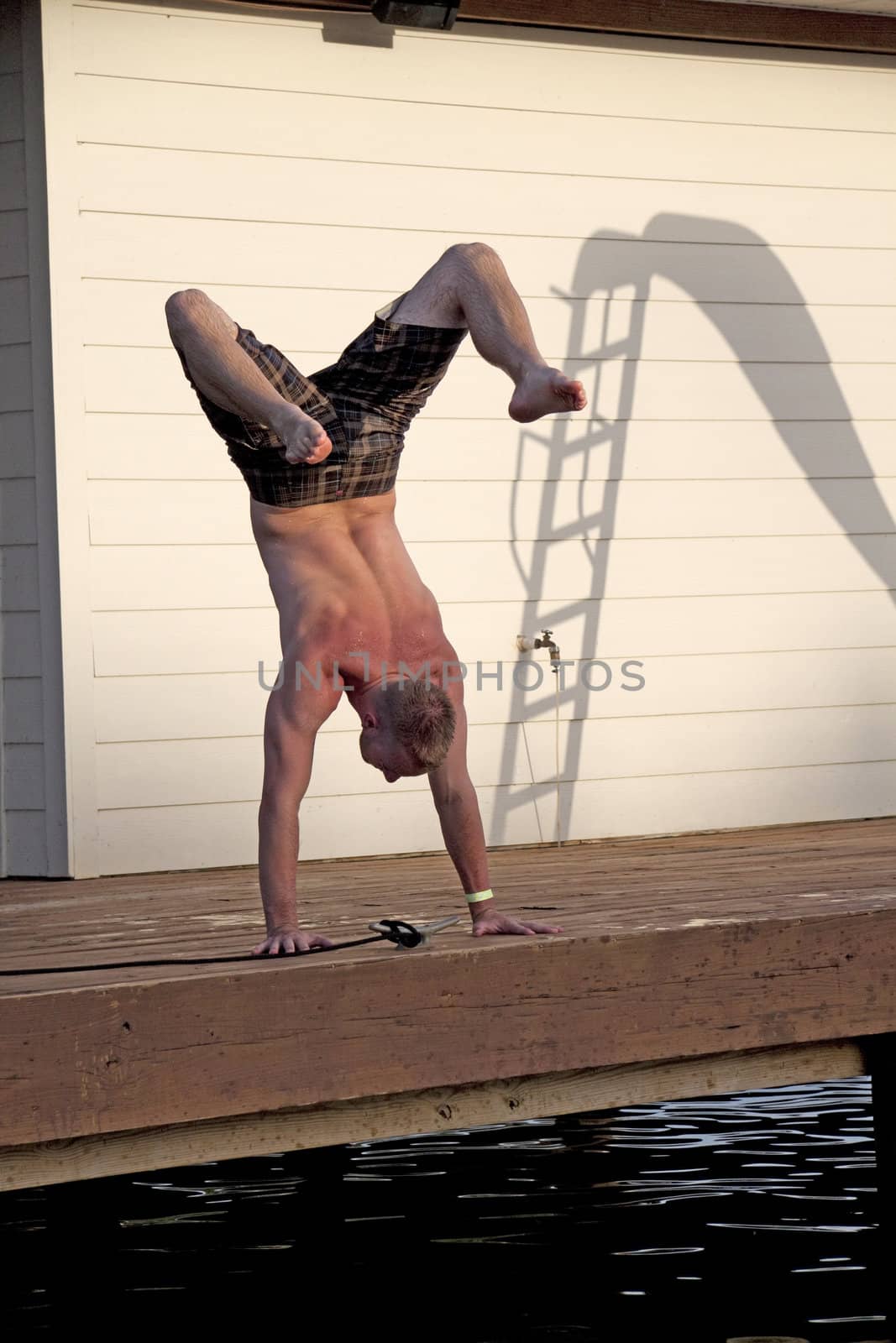 A man doing a handstand on a dock