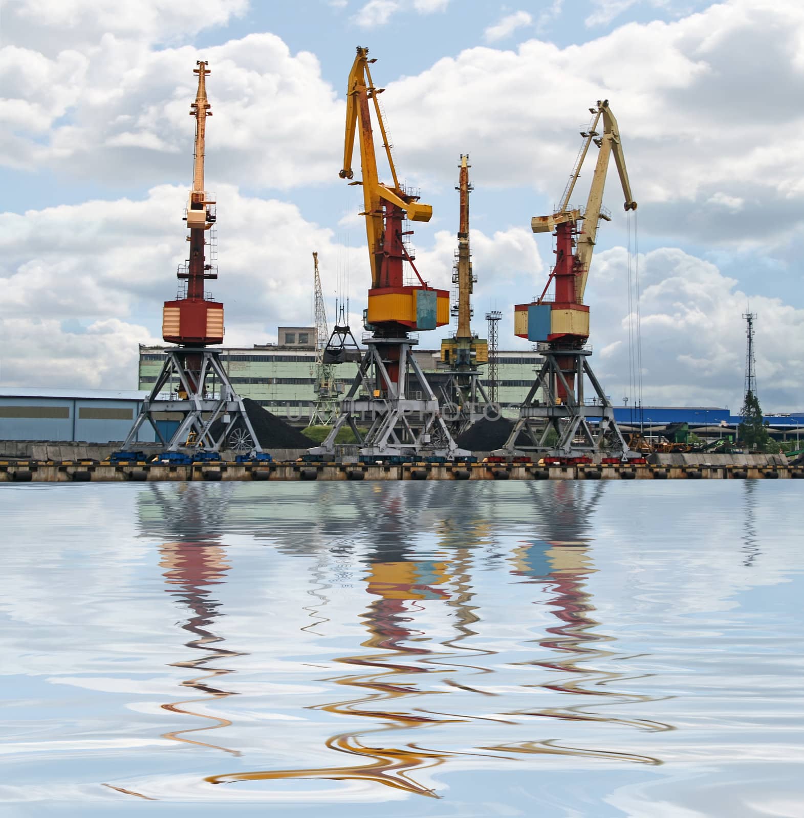 Container cranes for loading and unloading ships. Reflection over water.