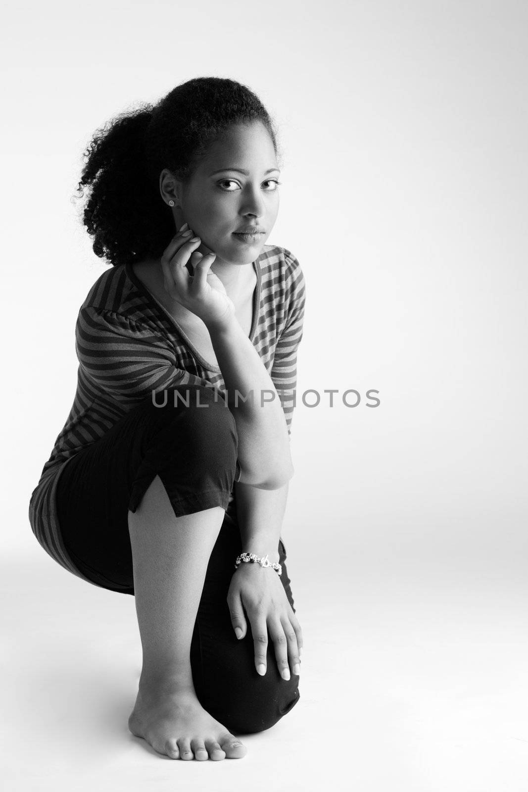 Young african girl sitting on her knee and looking into the lens