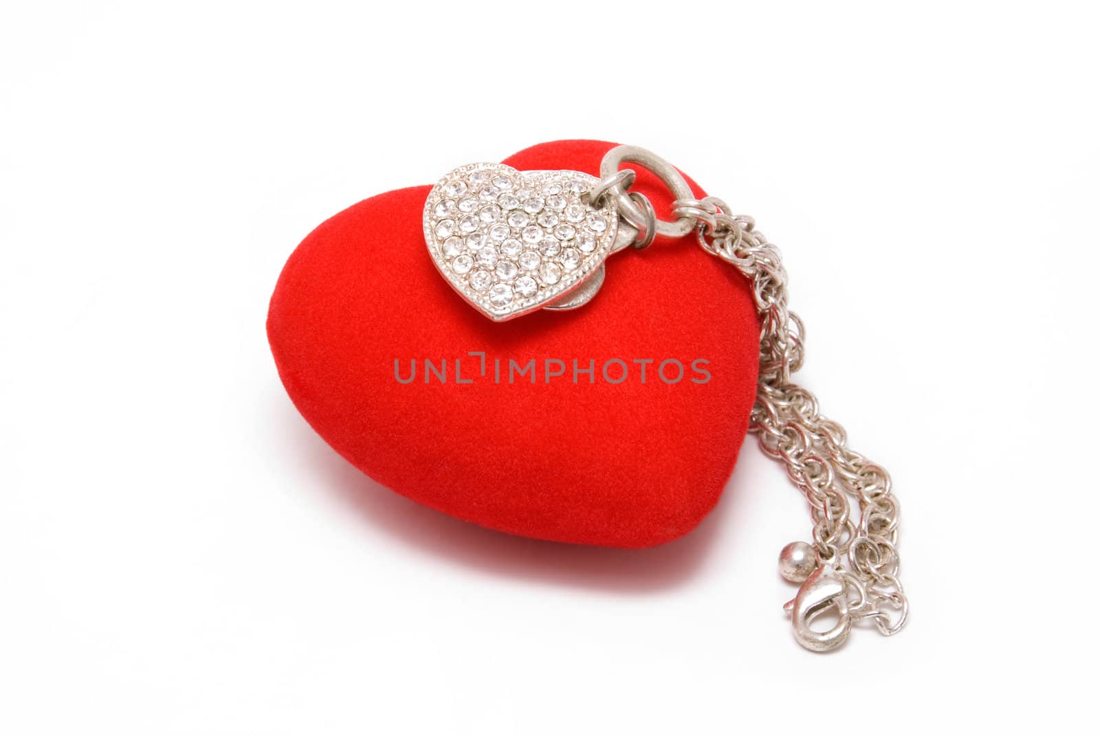 The silver chain with pendant as heart lays on red velvet heart