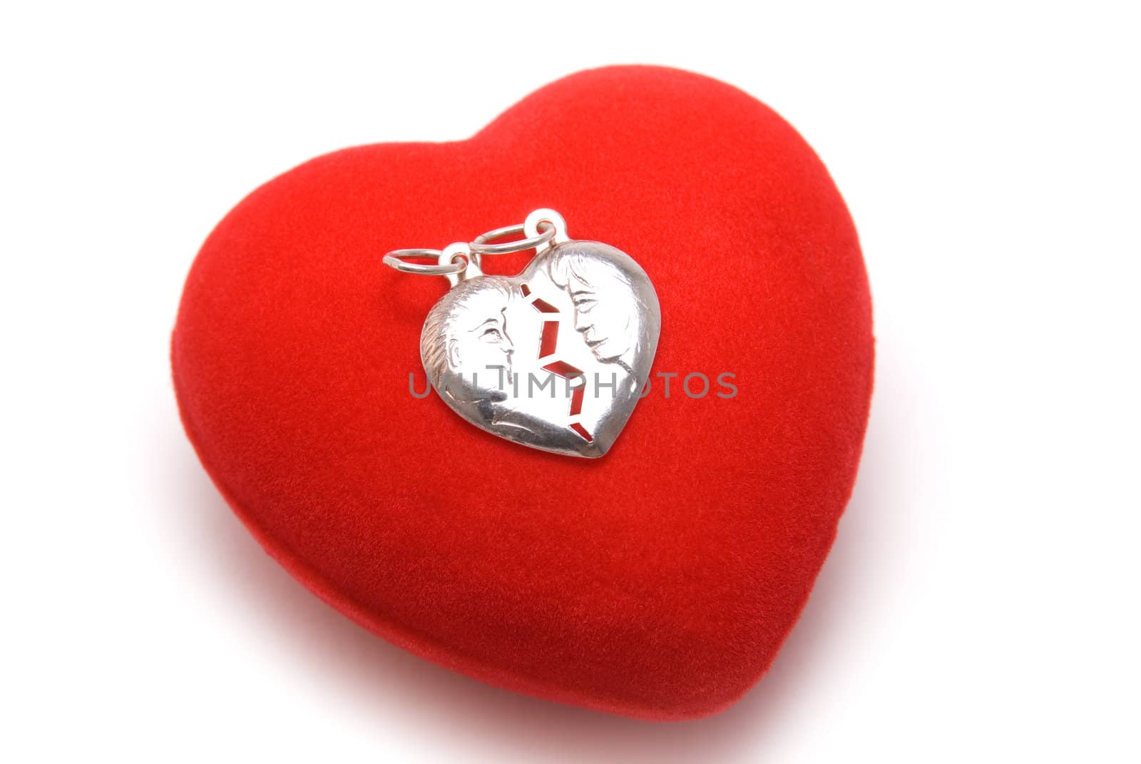 The silver medallion with profiles of the man and the woman lays on red velvet heart