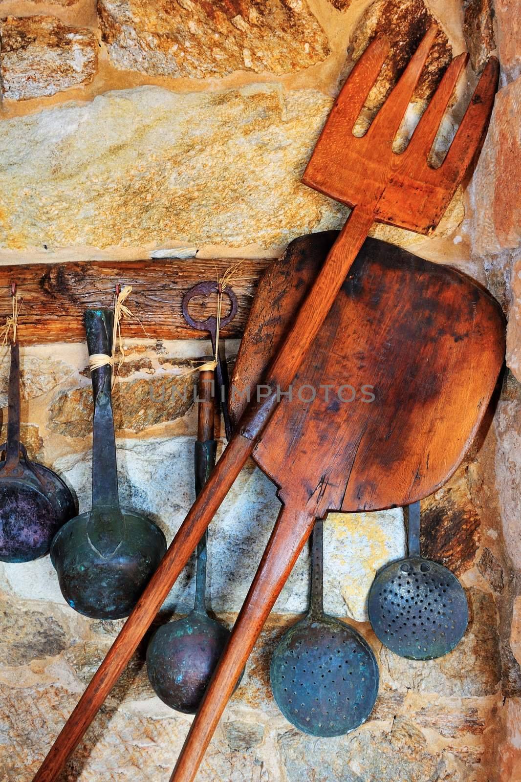 Picture of traditional oven and cooking utensils arranged against a stone wall