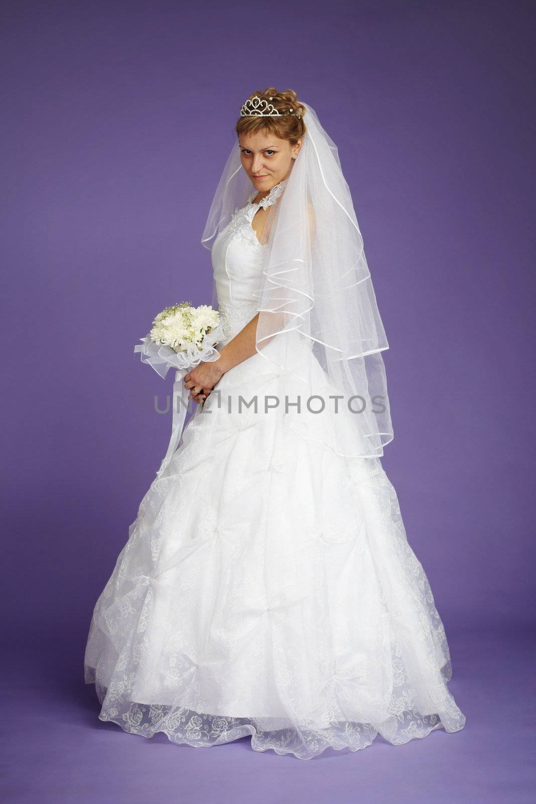 Young beautiful bride in a white dress on a purple background