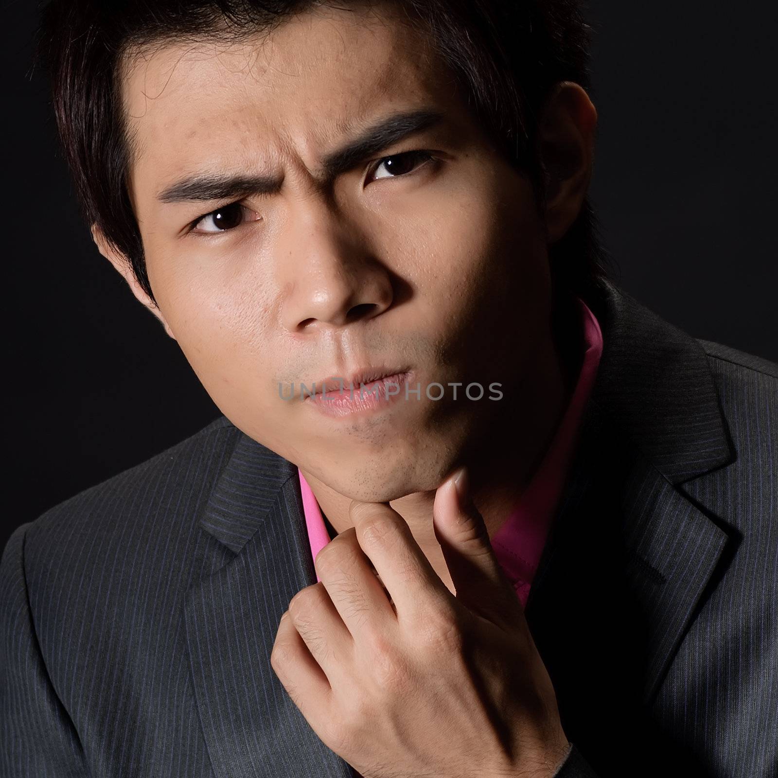 Closeup portrait of handsome businessman with pondering expression against black.