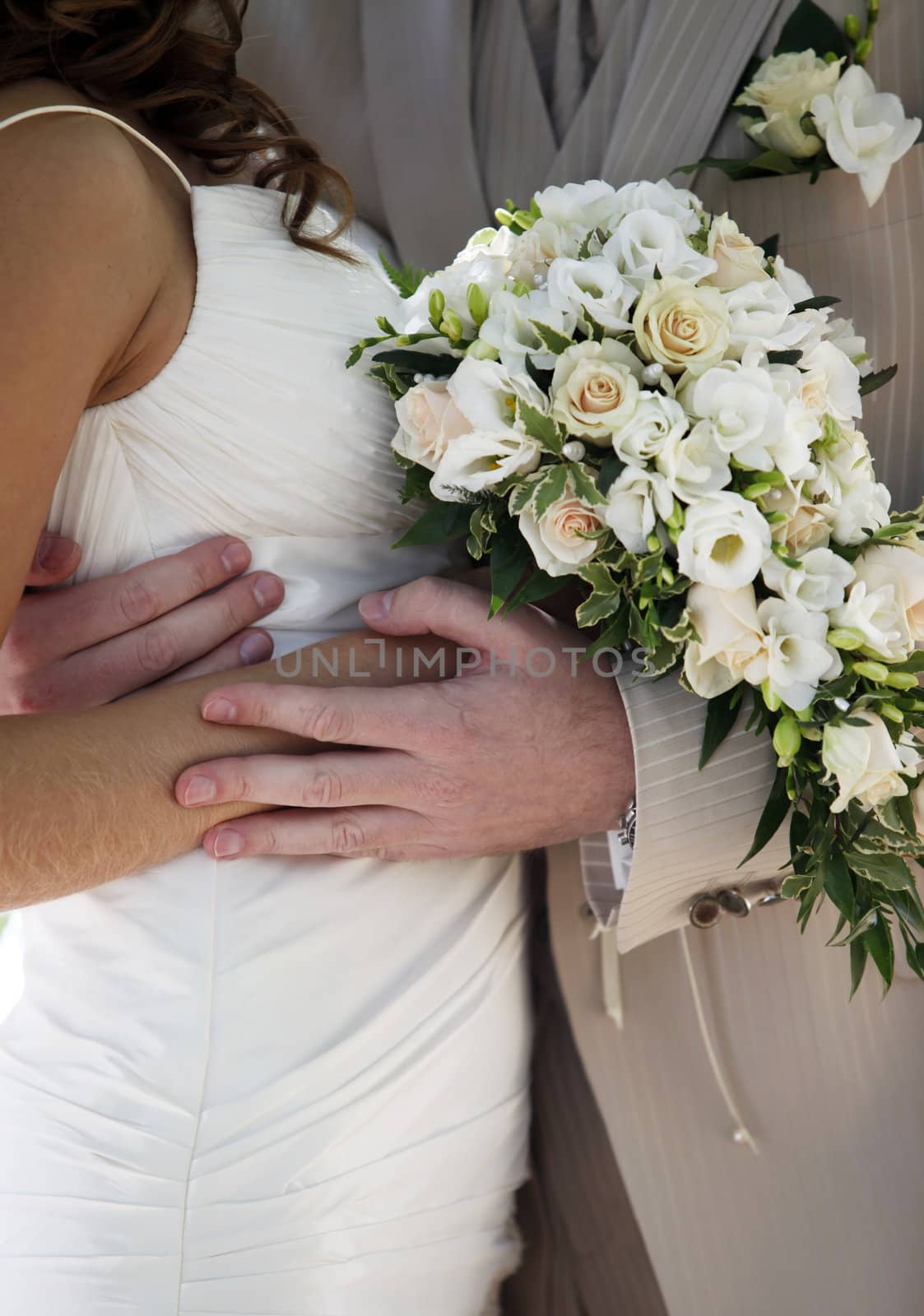 Bouquet of flowers on a background of a dress of the bride and a suit the groom.