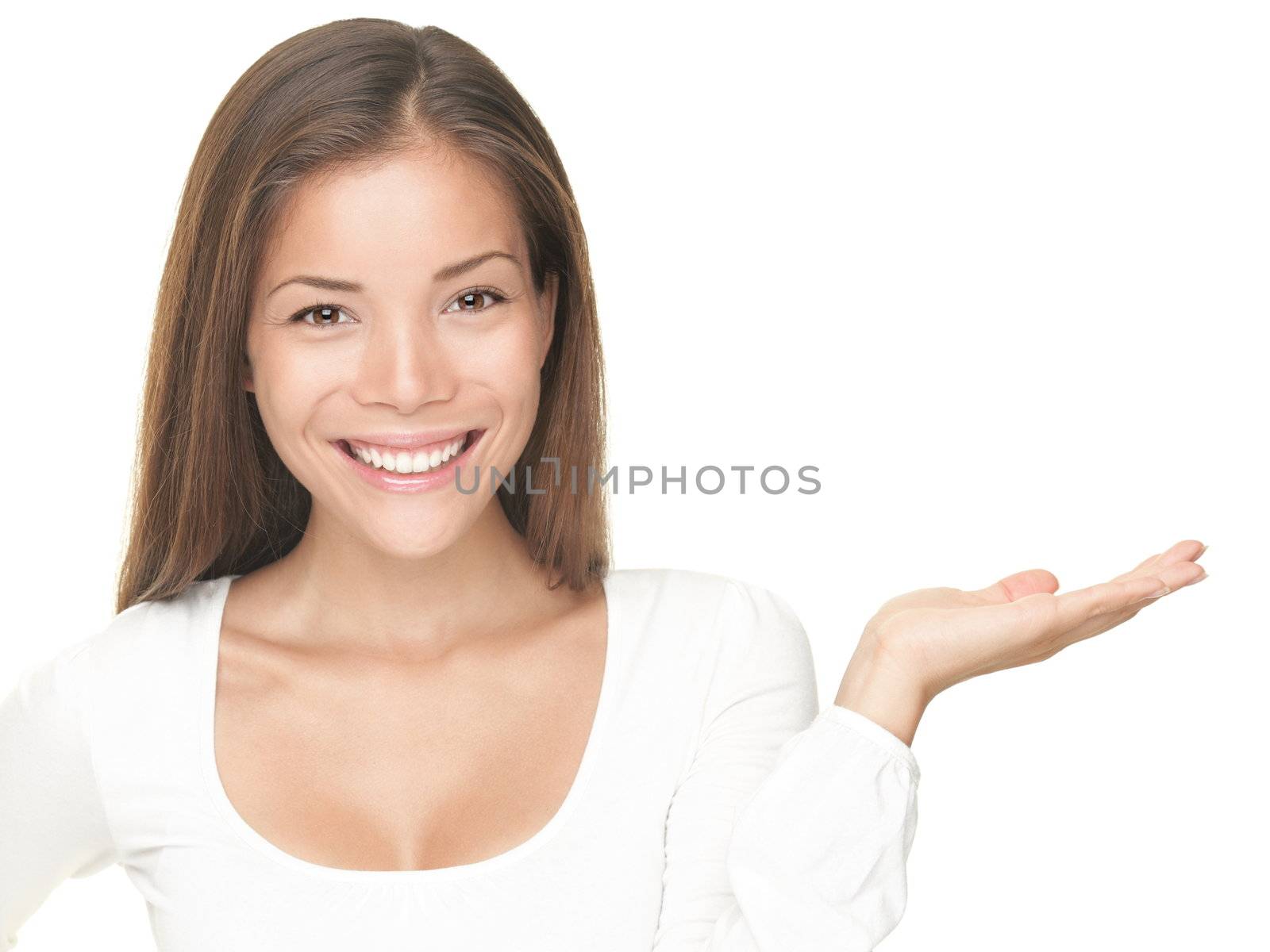 Smiling woman showing copy space for product with open hand palm - smiling friendly expression, Isolated on white background. Mixed Asian / Caucasian model. 