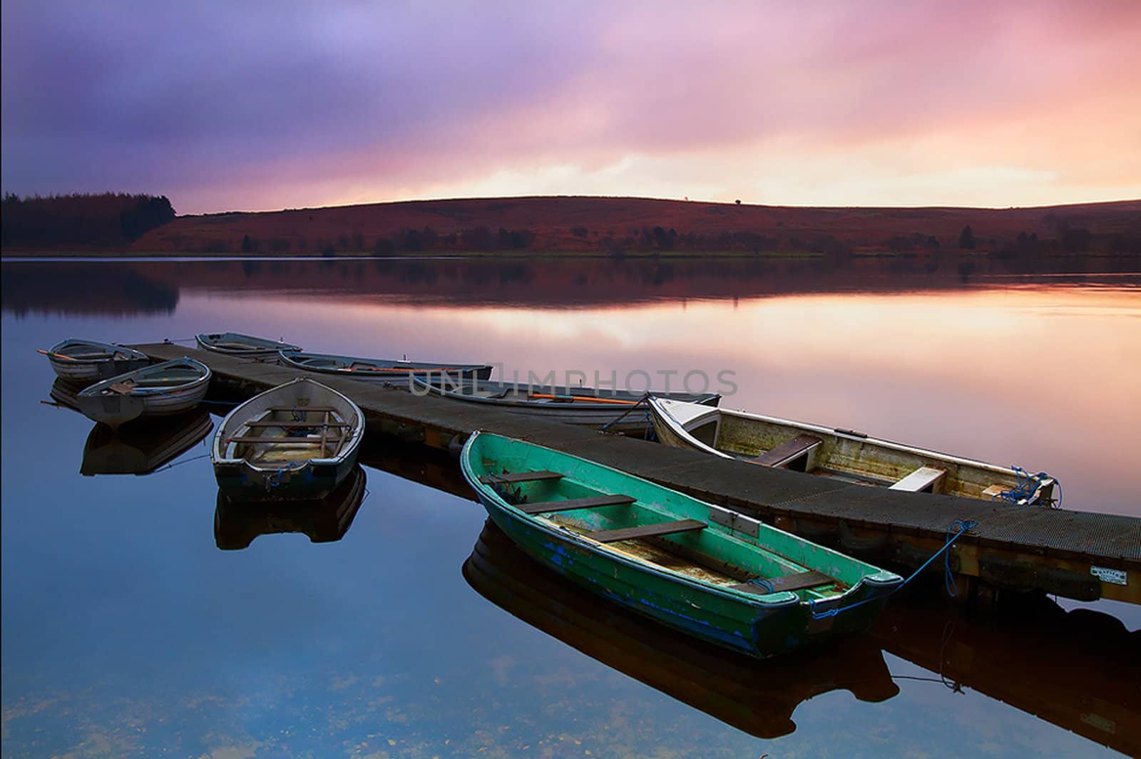 Rental rowboats tied to a pier at dawn