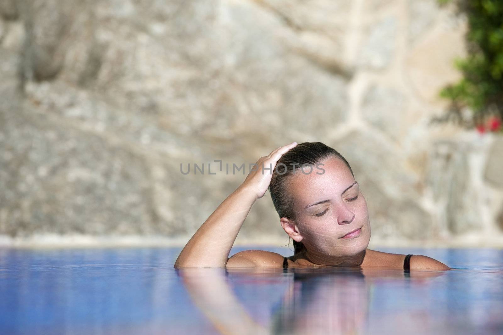 Young beautiful woman cools off in a pool during a hot summer afternoon