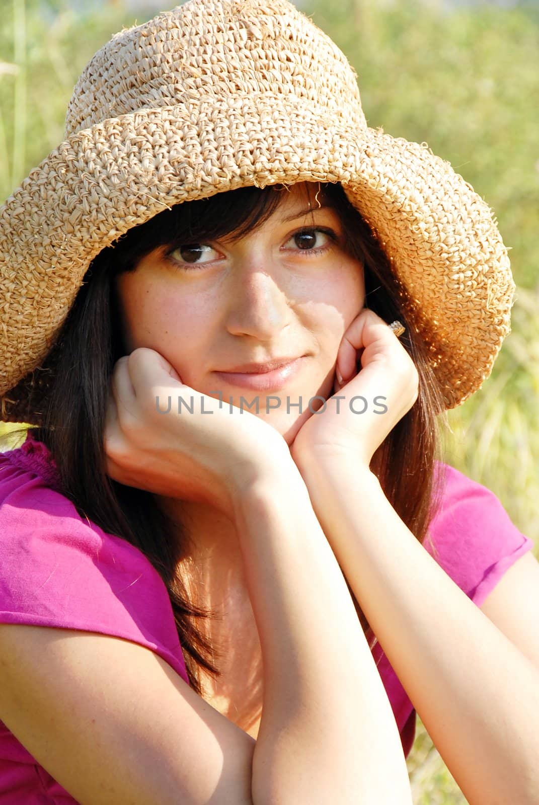 young brunette woman portrait outdoor in straw hat