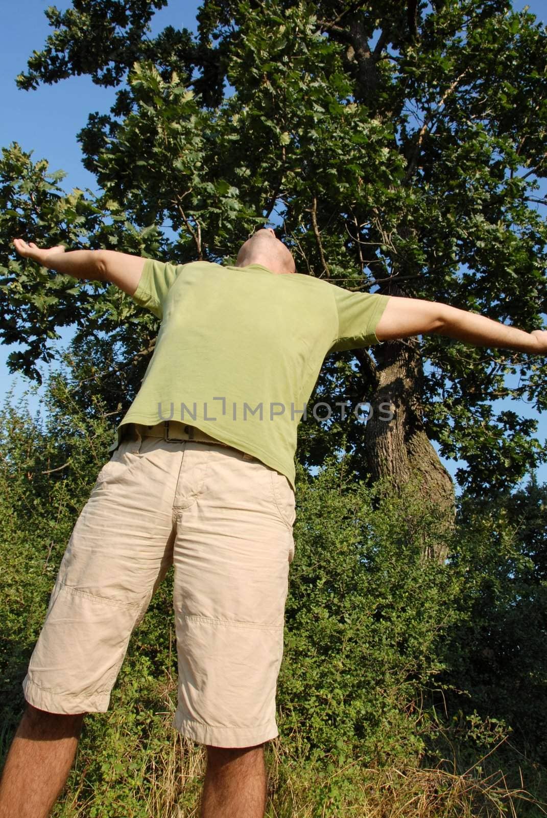 man with spreading hands standing outdoor over natural background