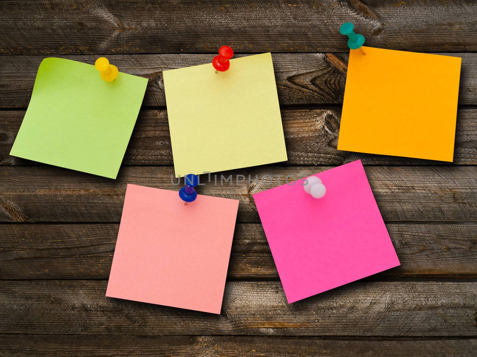 Multicolored stickers and notes and drawing pins at the wooden background