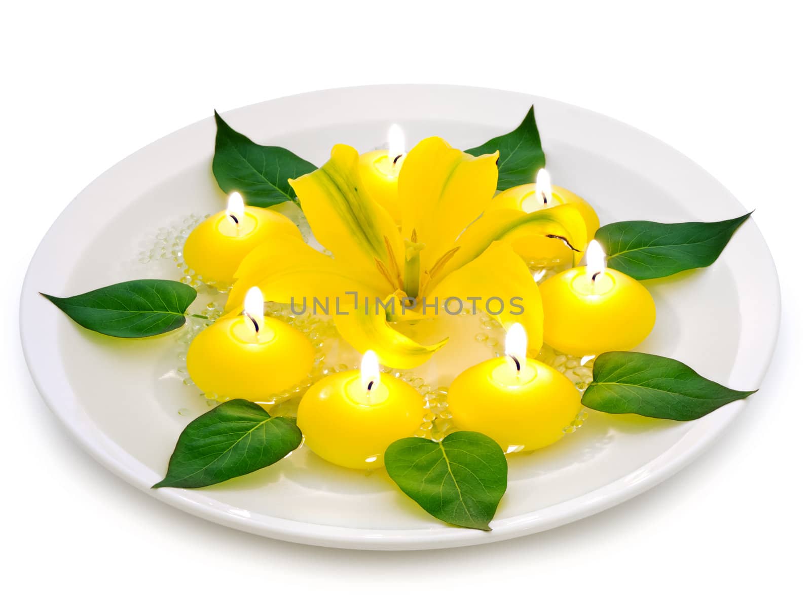 floral spa decoration with lily, candles and green leaves over white background 