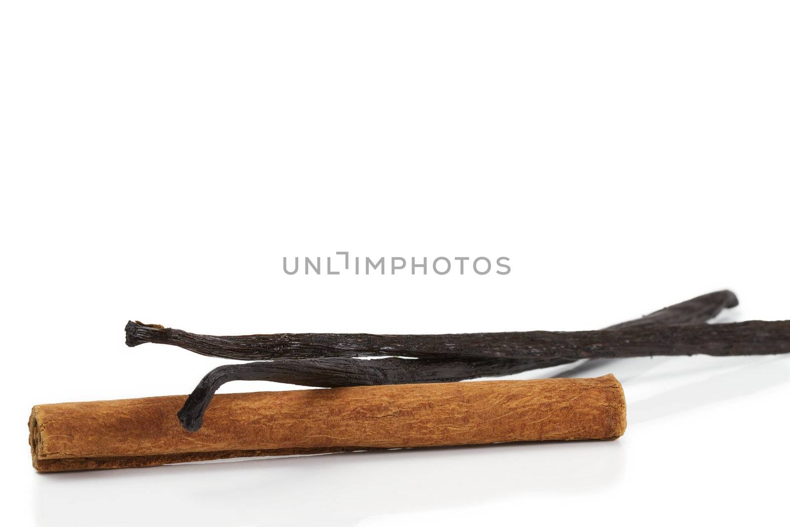 cinnamon stick and two vanilla beans on white background