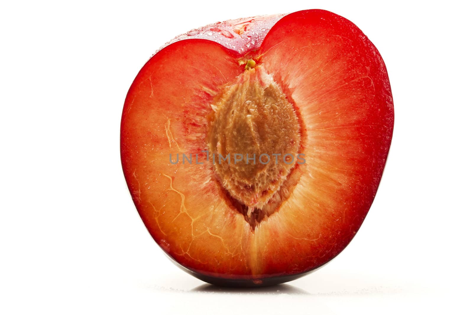 half wet plum with seed on white background