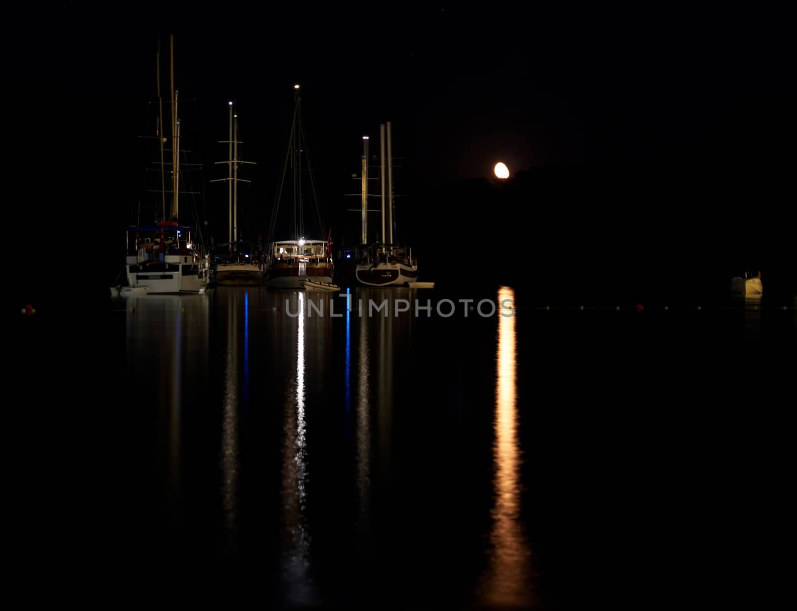 Boats at night with a moon on the dark background
